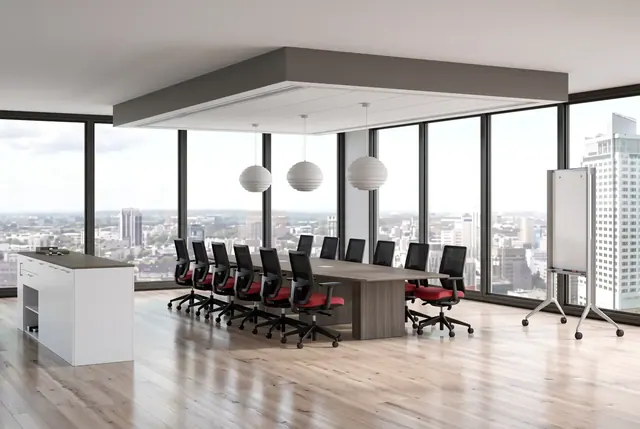 Bright conference room with a long meeting table, task chairs, and city views